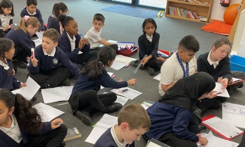 Children in Year 4 sat on the floor with paper based work